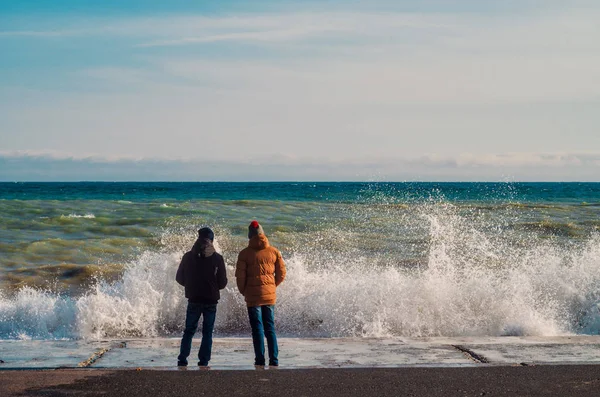 Boys look at the waves of the sea