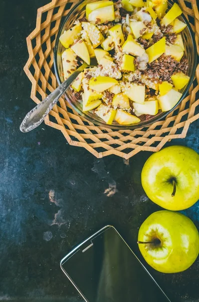 Two apples and oatmeal with seeds of cereals. phone