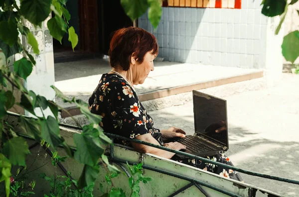 An elderly woman is sitting at the laptop. modern grandmother