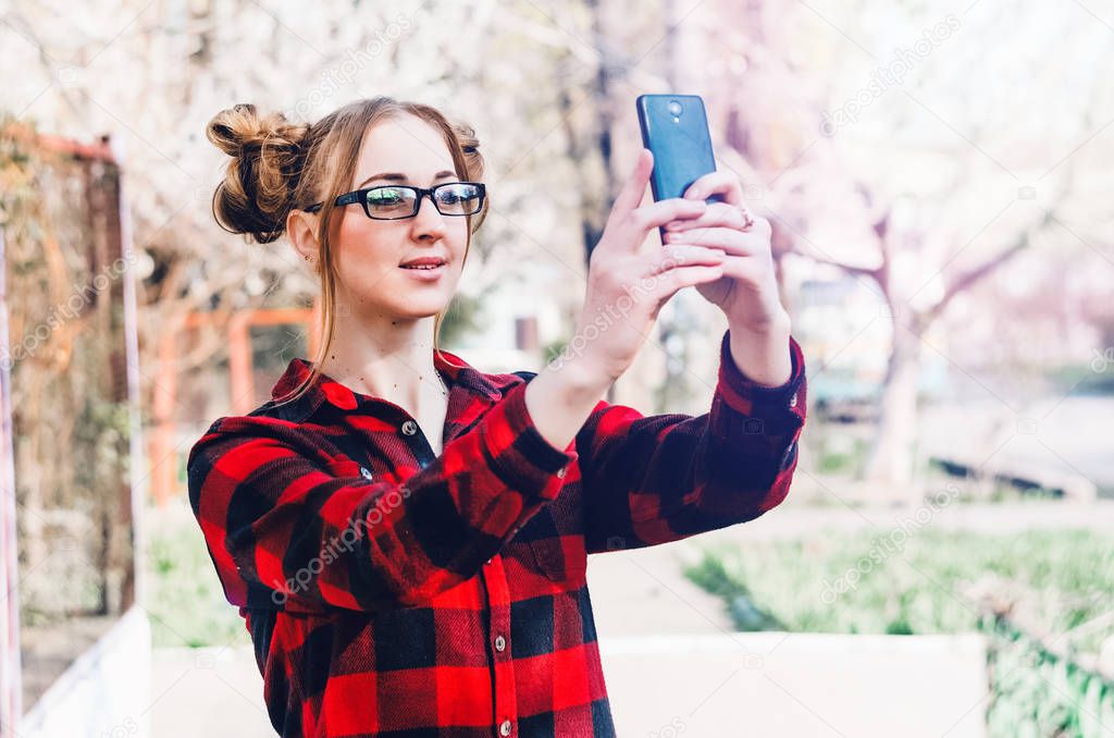 Girl posing on camera phone. holds the phone in his hands. glasses on the eyes
