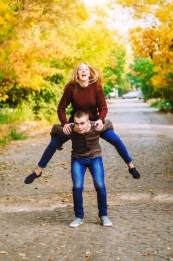 Bir kız bir adam biniyor. Bir adam atlamak. Birlikte yürüyüşe iyi eğlenceler. Sokakta yürümek.