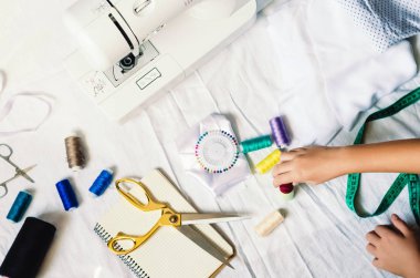 dikiş iş süreci. iğne işi için hazırlık. iş parçacığı, makine, santimetre, makas, not defteri, saç tokaları, iğneler, bez