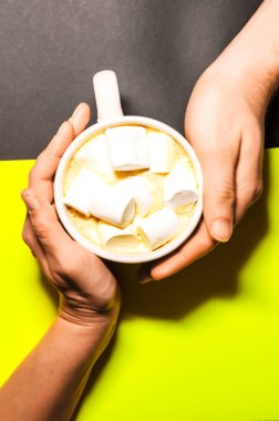 kız ve oğlan bir kupa düzenliyoruz. Aşk bir sembolü. sıcak kahve marshmallow ile. Yukarıdan görüntüleyin. arka plan siyah ve sarı.