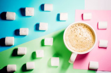 Mavi, yeşil, pembe bir arka plan üzerine krema olduğunu. Kupa köpük ile sıcak kahve ile