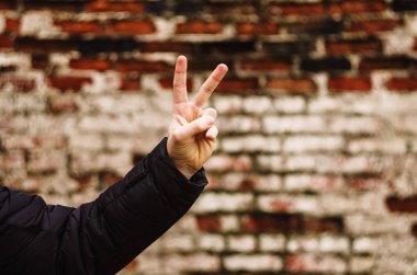 Barış jesti. erkek eli. Tuğla duvar.