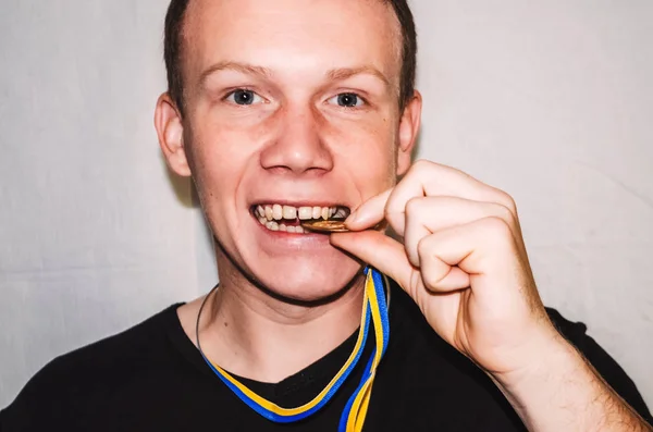 champion. portrait of a guy. bites a gold medal. athlete. professional. happy man. smile on the face
