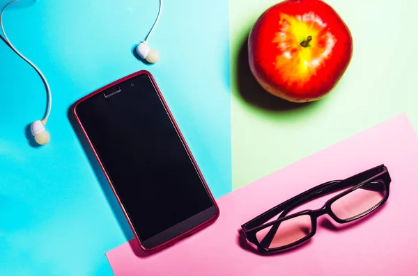 Telefono e bicchieri. spazio di lavoro. cuffie per ascoltare musica. tecnologie. cibo, mela rossa — Foto Stock