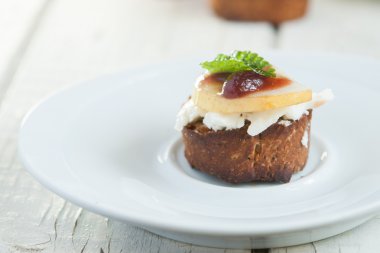 Bruschetta yanında da keçi peyniriyle armut beyaz plaka üzerinde