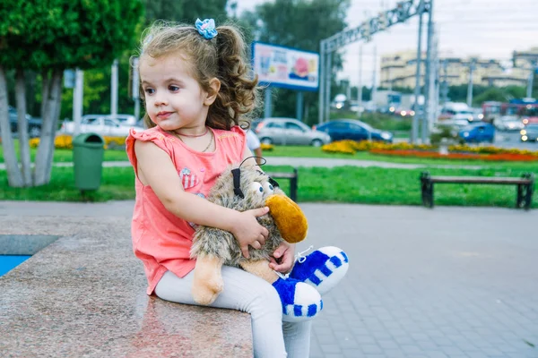 Pequena menina sentada no parque com brinquedo — Fotografia de Stock