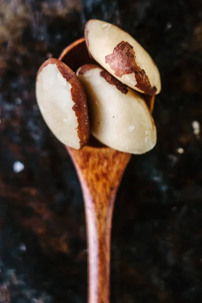 Nueces de Brasil en cuchara de madera sobre el fondo de metal negro . —  Fotos de Stock