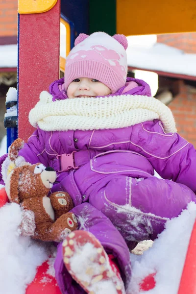Маленькая девочка играет на зимней площадке . — стоковое фото