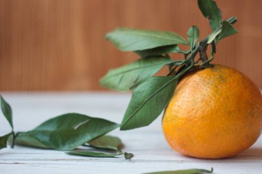 Beyaz ahşap bir tahtanın yapraklarıyla olgunlaşmış mandalina..