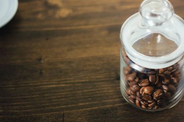Şeffaf cam kahve sürahi kahve çekirdekleri ile koyu ahşap masa üzerinde dolu..