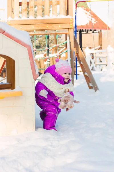 Маленькая девочка играет на зимней площадке . — стоковое фото