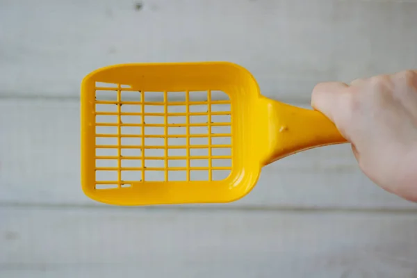 Cuchara de plástico amarillo para limpiar la camada de mascotas sobre el fondo de madera — Foto de Stock