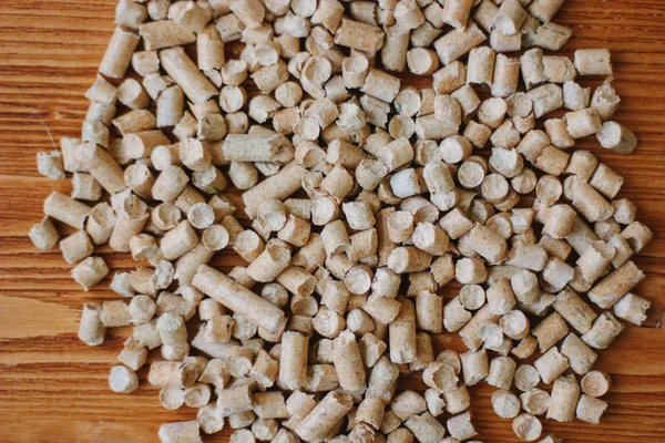 Biopalivo - malé dřevěné pelety na dřevěném stole. — Stock fotografie