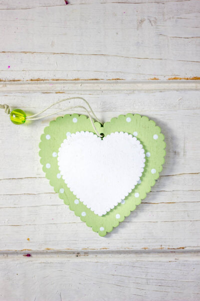 Два деревянных сердца - белое и зеленое на деревянном фоне
