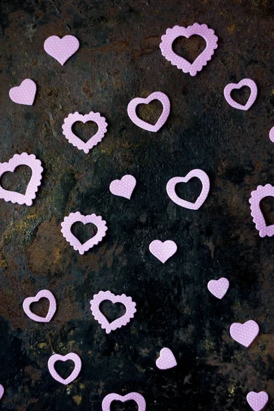 Valentine\'s day background - purple hearts confetti on black rustic background