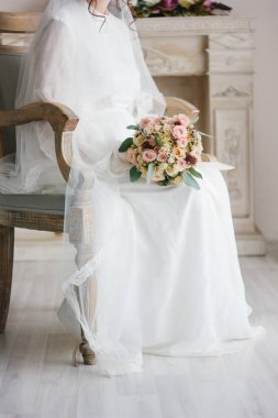 Güzel düğün sahnesi - sandalyede oturan ve düğün buket tutan gelin.