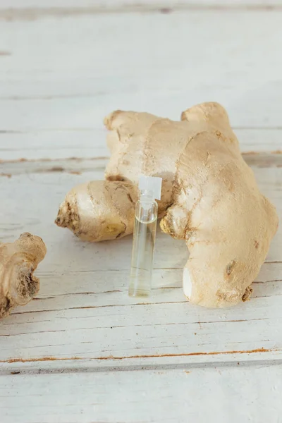 Gember essentiële olie in glazen fles met gember wortel achter. — Stockfoto