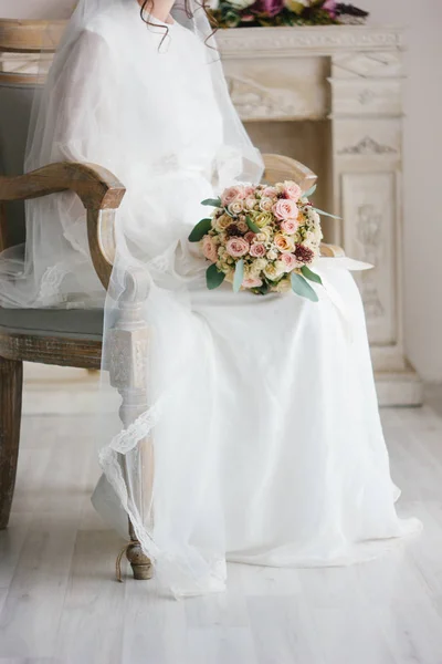 Cena de casamento bonita noiva sentada na cadeira e segurando buquê de casamento . — Fotografia de Stock