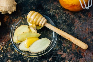 Tatlım kaşık ile cam tabakta bal ve zencefil kökü bit.