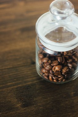 Şeffaf cam kahve sürahi kahve çekirdekleri ile koyu ahşap masa üzerinde dolu..