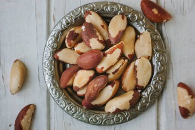 Brezilya fıstığı Beyaz ahşap masa üzerinde metal plaka.