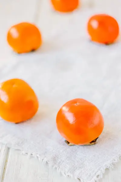 Group of ripe persimmons on white fabric material. — Stock Photo, Image