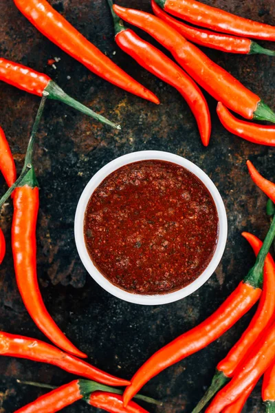 Red mexican salsa surrounded by red hot chili peppers.
