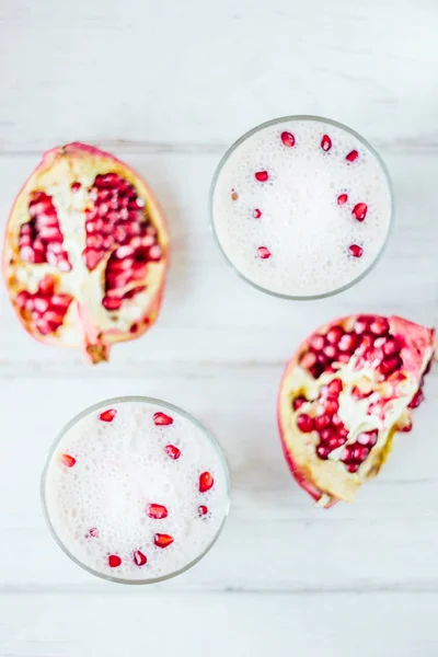 El lassi tradicional indio - la bebida fría yougurt sobre la mesa blanca con las semillas de granada. Vista superior . — Foto de Stock