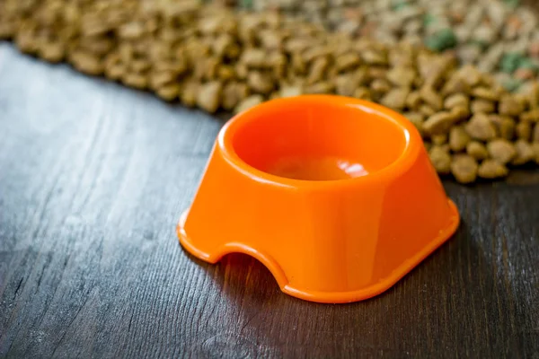 애완 동물용 음식을 담는 작은 오렌지색 그릇과 마른 음식의 배경. — 스톡 사진