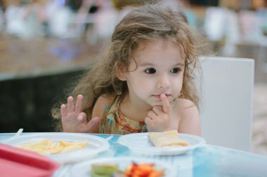 Küçük kız kafede ya da restoranda yemekle eğleniyor..