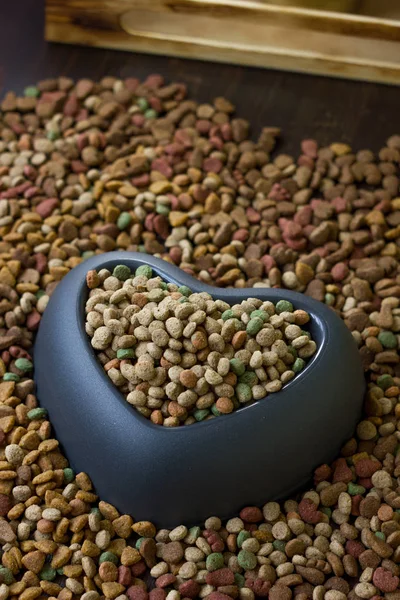 Heart pet bowl filled by dry pet food.