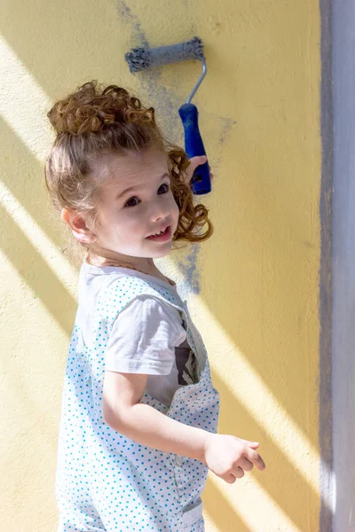 Menina criança pinta parede por rolo de pintura — Fotografia de Stock