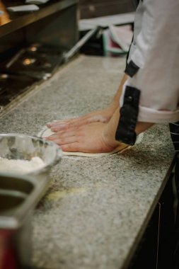 Şef İtalyan pizzacıda pizza için hamur hazırlıyor..