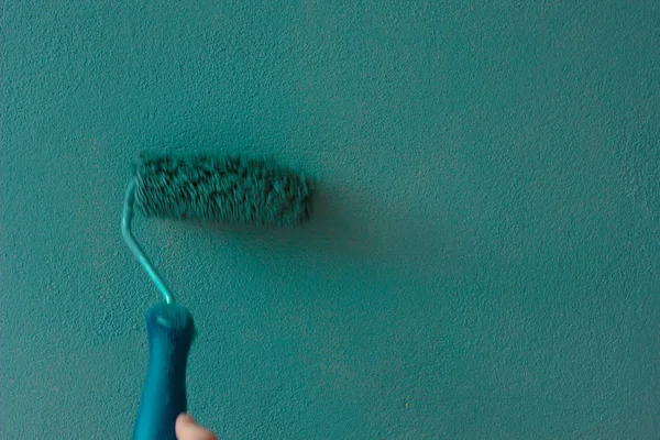 Hand met de verfroller over de groene muur. — Stockfoto