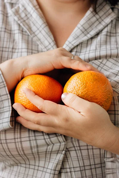 Woman holding two ripe oranges in her hands. — Stock Photo, Image