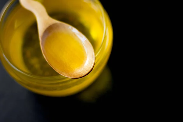 Fresh ghee butter in a wooden spoon over black stone background. — Stock Photo, Image