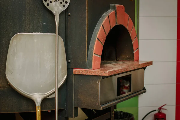 Palas de pizza metálicas tradicionales cerca del horno de pizza . — Foto de Stock