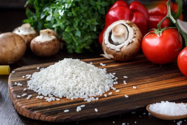 Ahşap mutfak kurulu ile pirinç üzerine, arounded sebze ve baharatlar.