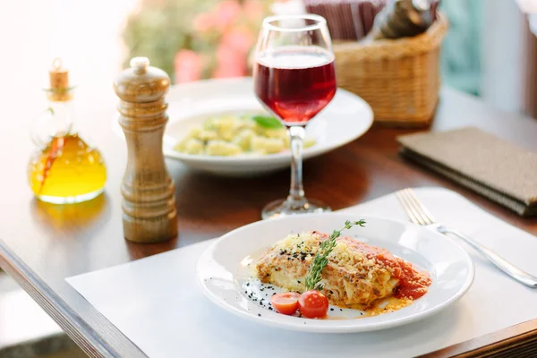 Итальянская кухня - вкусная лазанья в белой тарелке на столе с красным вином . — стоковое фото