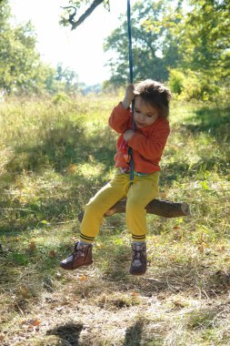 İlkel elli küçük kız, sonbahar parkında salıncak yaptı..
