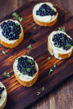 Ahşap mutfak kartı ekmek parçaları üzerinde siyah havyar.