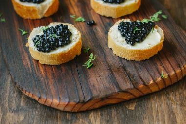 Ahşap mutfak kartı ekmek parçaları üzerinde siyah havyar.