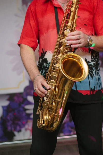 Saxophone player with the saxophone in arms, playing with it.