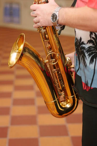 Saxophone player with the saxophone in arms, playing with it.