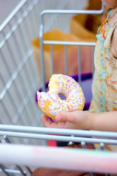 Mano con rosquilla mordida. Chica sosteniendo donut en brazo — Foto de Stock