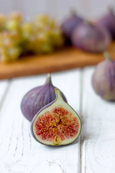 Metà del fico sul tavolo di legno bianco con altri fichi e frutti . — Foto Stock