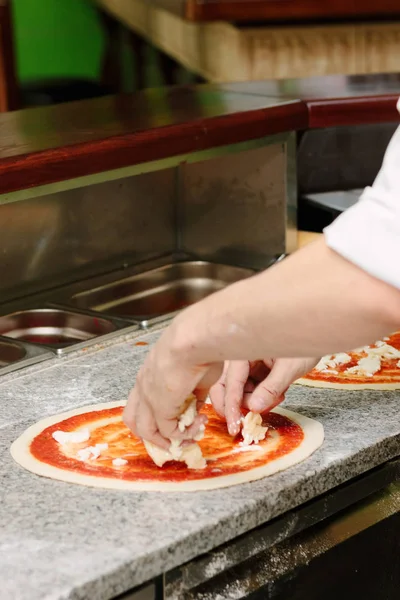 Jefe poniendo ingredientes en la parte superior de la pizza . — Foto de Stock
